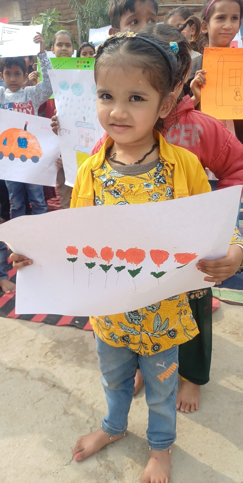 A young girl at a Shikshadwar community event proudly holds up her own artwork
